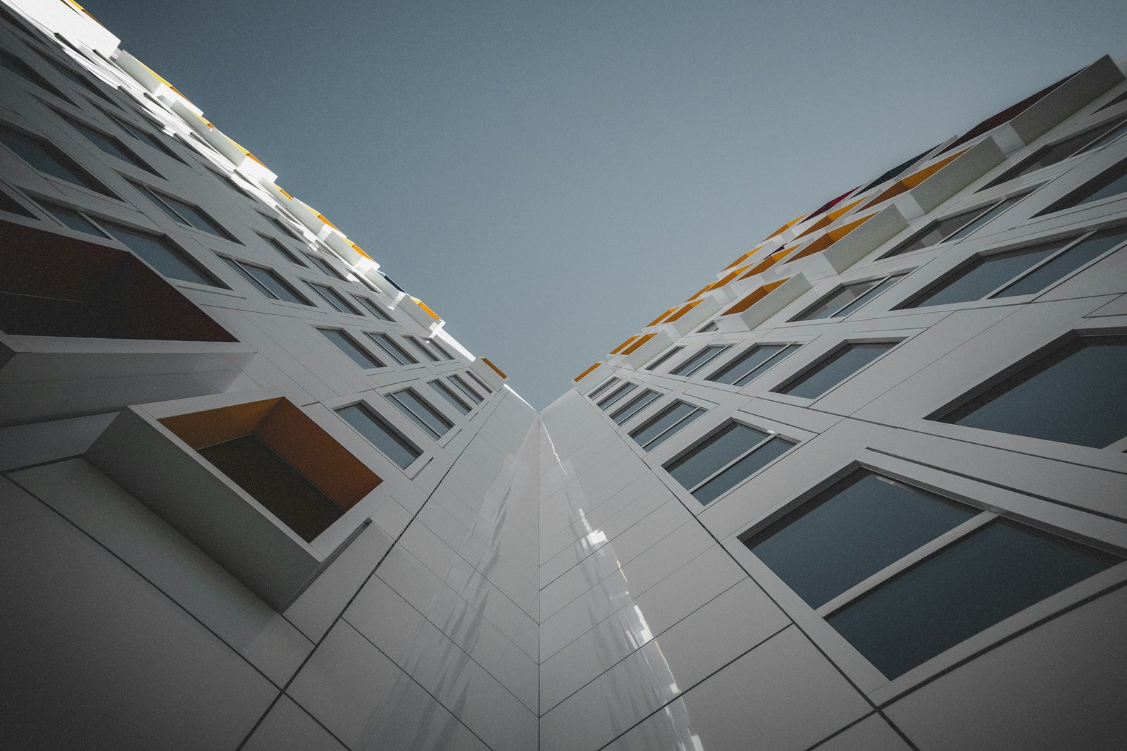 Upward view of a completed mid-rise building facade with regular window bays against a clear sky.