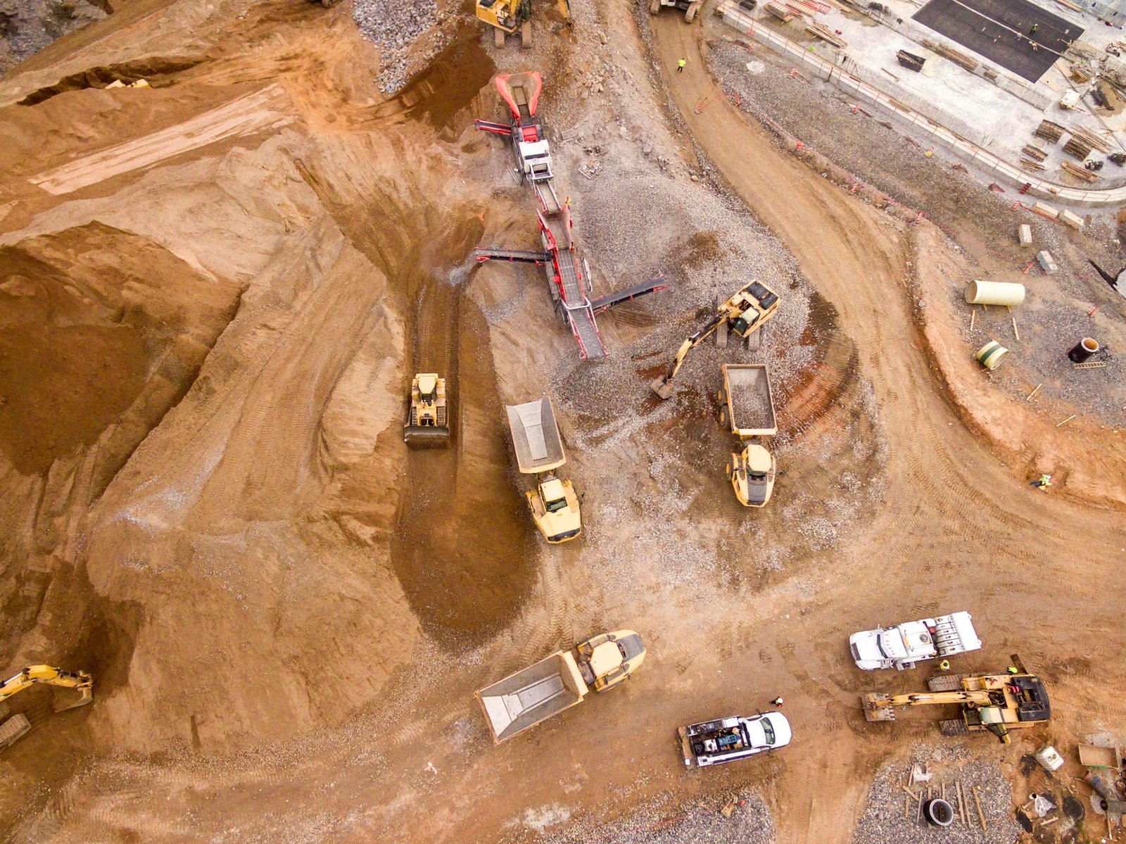 Aerial view of an active earthwork site showing mass grading, haul roads, scrapers and material stockpiles.